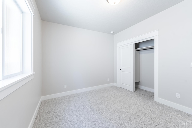 unfurnished bedroom featuring carpet, a closet, and baseboards