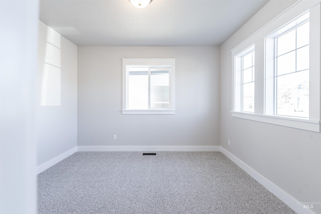 carpeted empty room featuring baseboards and visible vents