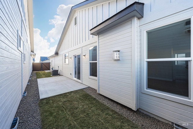 exterior space featuring central AC, board and batten siding, a patio area, and fence