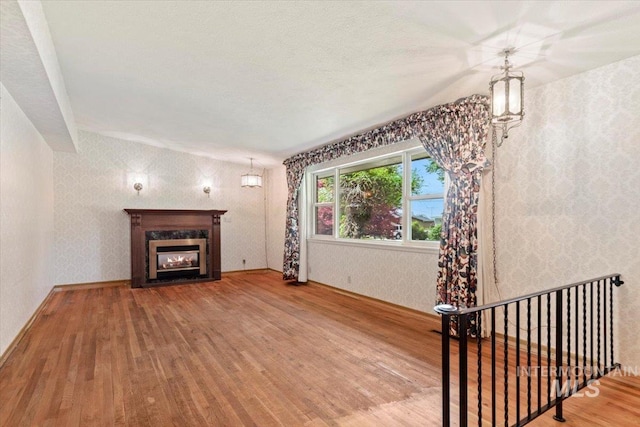 10809 W Cruser, Boise, ID 83709 - unfurnished living room with wood finished floors, wallpapered walls, and a high end fireplace