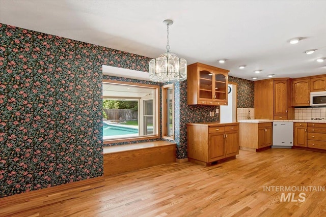 10809 W Cruser, Boise, ID 83709 - kitchen featuring white appliances, wallpapered walls, a chandelier, light wood finished floors, and glass insert cabinets
