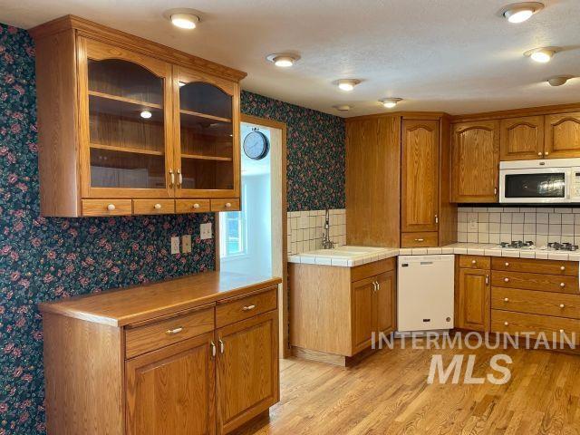 10809 W Cruser, Boise, ID 83709 - kitchen with white appliances, wallpapered walls, brown cabinets, light wood-style flooring, and a sink