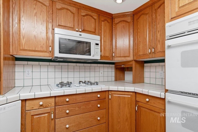 10809 W Cruser, Boise, ID 83709 - kitchen featuring white appliances, decorative backsplash, brown cabinetry, and light countertops
