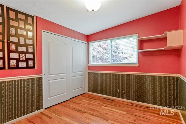 10809 W Cruser, Boise, ID 83709 - unfurnished bedroom with wainscoting, wood finished floors, a closet, and baseboards