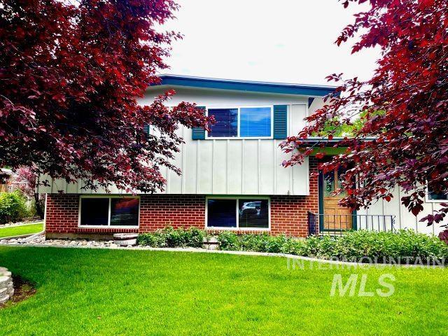 10809 W Cruser, Boise, ID 83709 - view of front of home with board and batten siding, a front lawn, and brick siding