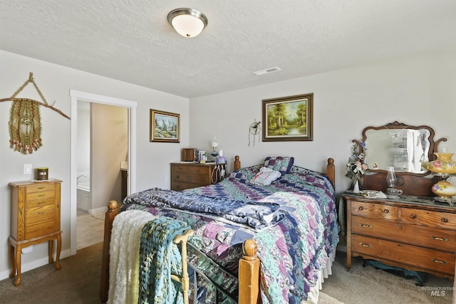 carpeted bedroom featuring ensuite bath and a textured ceiling