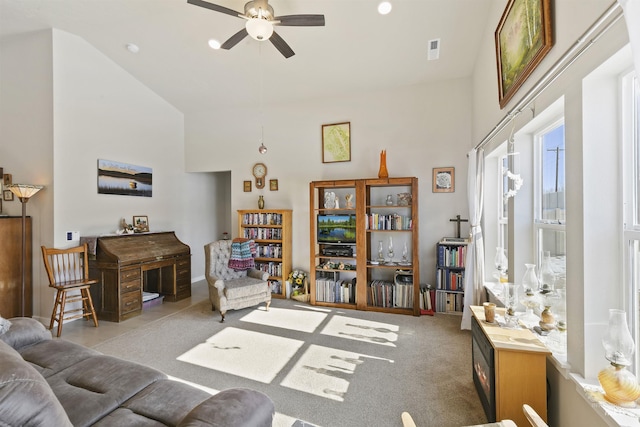 living room with ceiling fan, light colored carpet, and a high ceiling