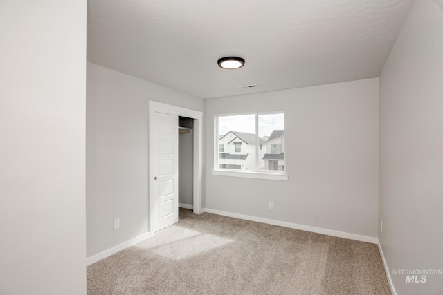 unfurnished bedroom with light colored carpet and a closet