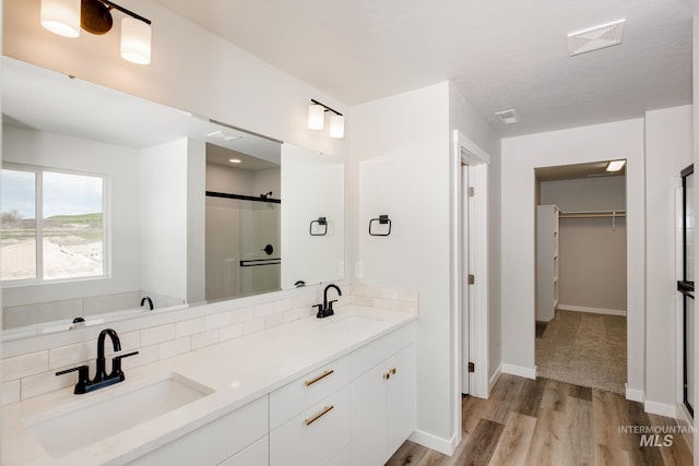 bathroom featuring tasteful backsplash, hardwood / wood-style floors, vanity, and walk in shower