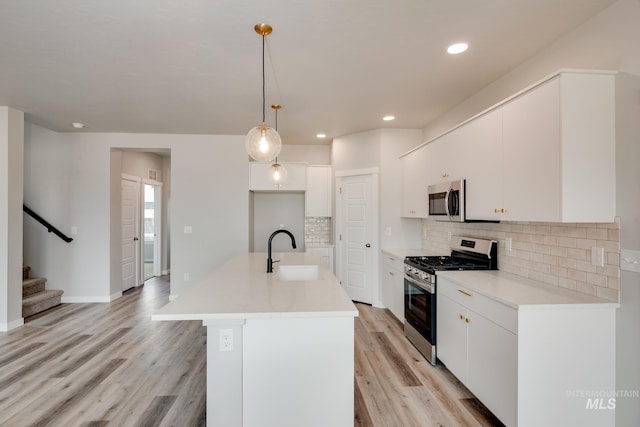 kitchen featuring pendant lighting, stainless steel appliances, white cabinetry, and sink