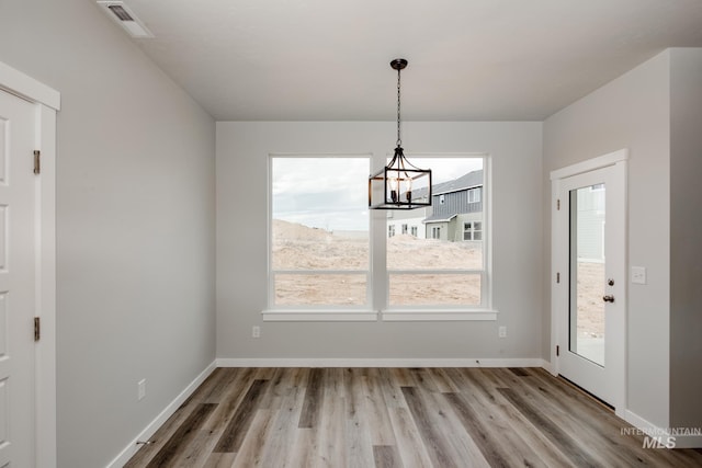 unfurnished dining area featuring hardwood / wood-style floors and an inviting chandelier