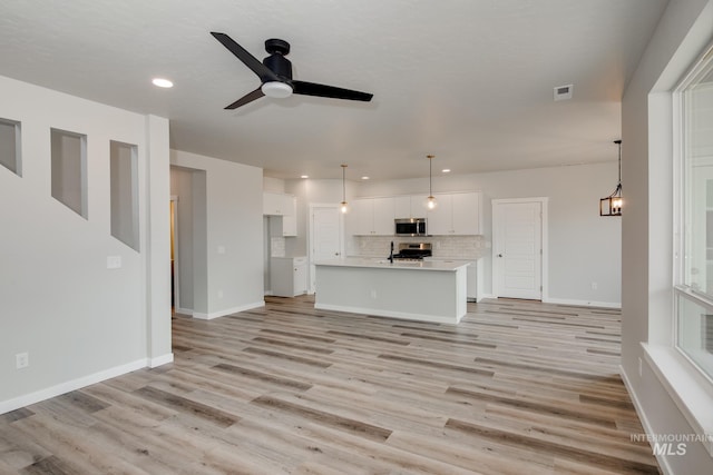 unfurnished living room with ceiling fan and light wood-type flooring