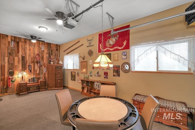 recreation room featuring ceiling fan, wood walls, and carpet floors