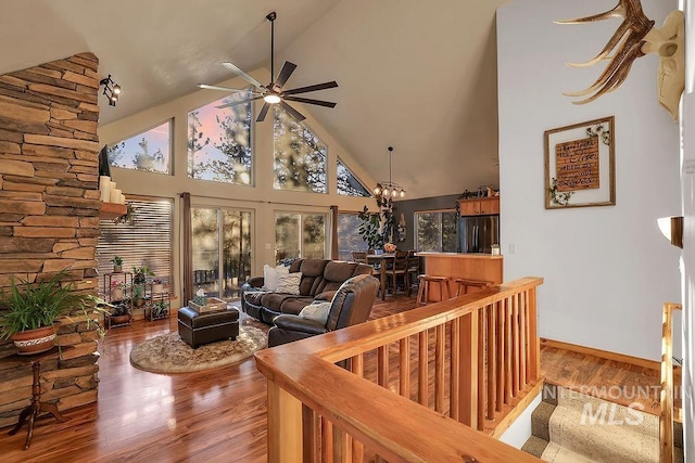 living room featuring hardwood / wood-style floors, high vaulted ceiling, and ceiling fan with notable chandelier