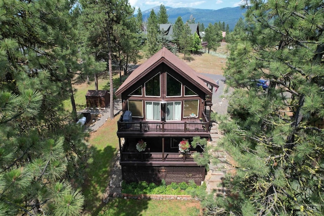 rear view of property featuring a deck with mountain view and a yard