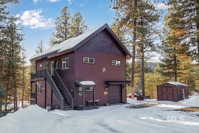 snow covered property with a storage unit and a garage