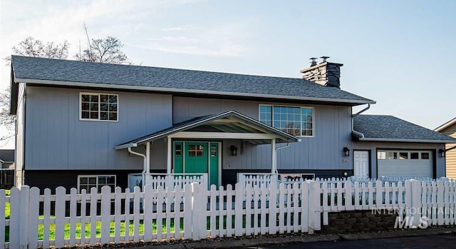 view of front of property with an attached garage, a chimney, a fenced front yard, and a shingled roof
