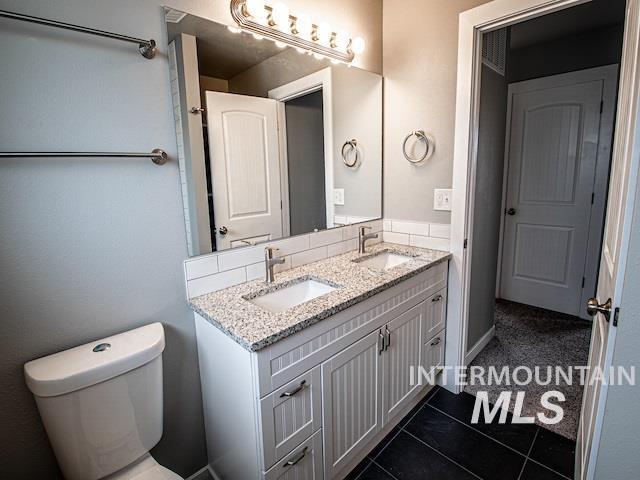 bathroom featuring tile patterned flooring, double vanity, and toilet