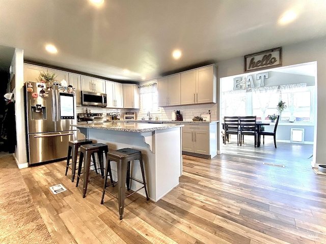 kitchen featuring appliances with stainless steel finishes, light wood-type flooring, a breakfast bar, a kitchen island, and recessed lighting