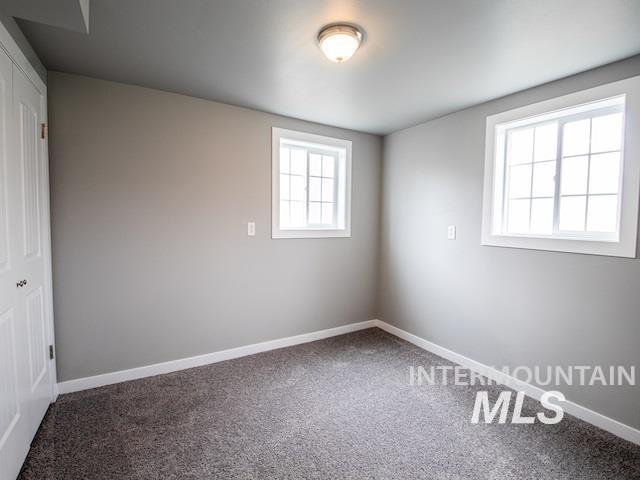 carpeted empty room featuring baseboards