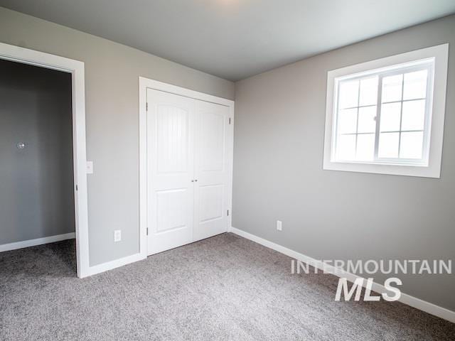 unfurnished bedroom with carpet flooring, baseboards, and a closet