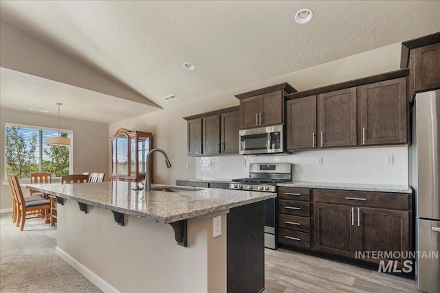 2510 Duchess Trl, Emmett, ID 83617 - kitchen with appliances with stainless steel finishes, a sink, a breakfast bar, lofted ceiling, and light stone counters