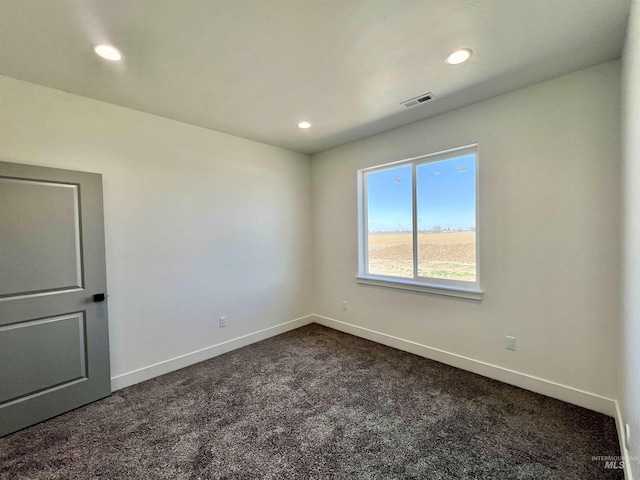 spare room with recessed lighting, dark colored carpet, visible vents, and baseboards