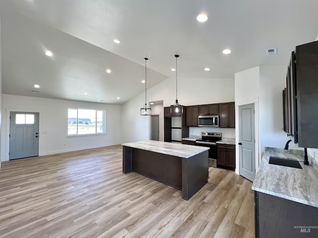 kitchen with vaulted ceiling, dark brown cabinets, stainless steel appliances, light wood finished floors, and a kitchen island