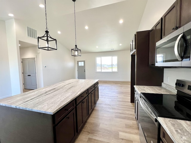 kitchen with light wood-type flooring, vaulted ceiling, visible vents, a kitchen island, and appliances with stainless steel finishes