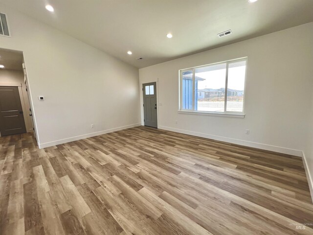 unfurnished living room with recessed lighting, wood finished floors, visible vents, and baseboards