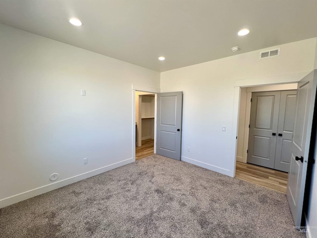 unfurnished bedroom featuring carpet flooring, baseboards, visible vents, recessed lighting, and a closet
