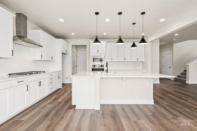 6117 N Torva Ave, Meridian, ID 83646 - kitchen featuring wall chimney range hood, stainless steel appliances, light wood-style floors, light countertops, and recessed lighting