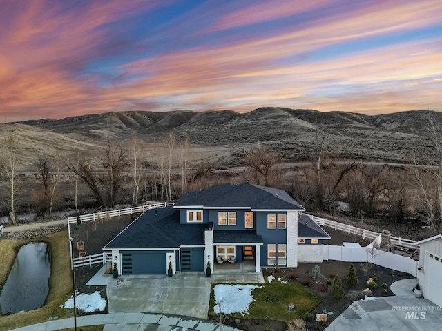 view of front of house featuring concrete driveway, a fenced backyard, a mountain view, and an attached garage