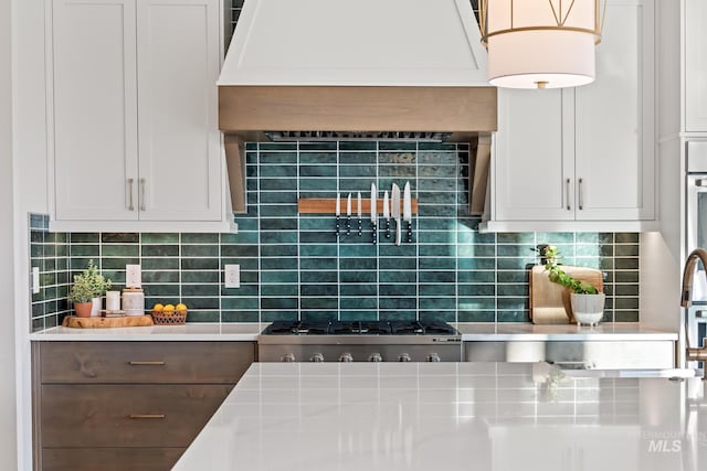 kitchen featuring light countertops, custom exhaust hood, backsplash, and stainless steel gas stovetop