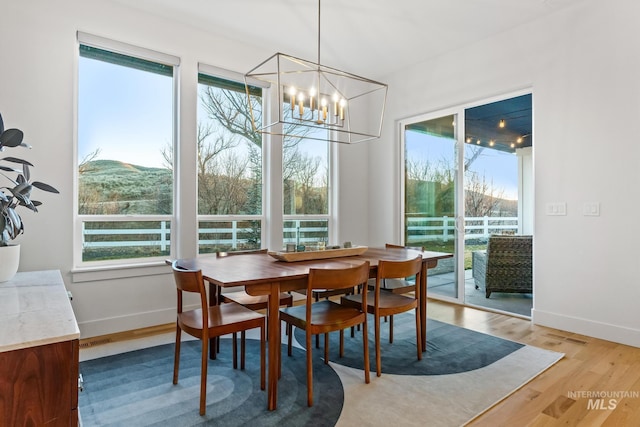 dining area with a chandelier, baseboards, and light wood finished floors