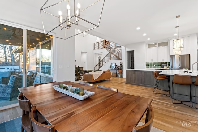 dining room with stairway, recessed lighting, floor to ceiling windows, and light wood-style flooring