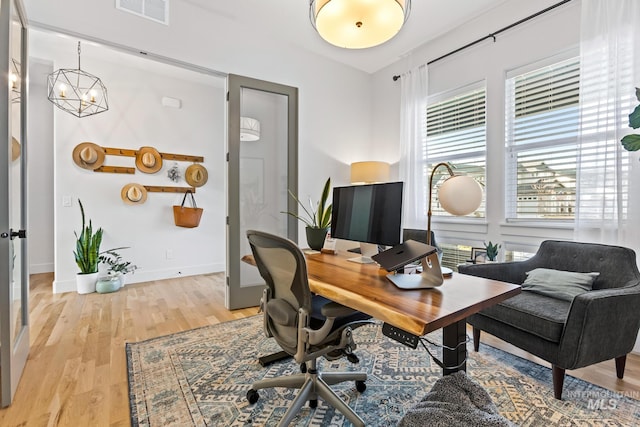 office space with a chandelier, light wood-type flooring, visible vents, and baseboards