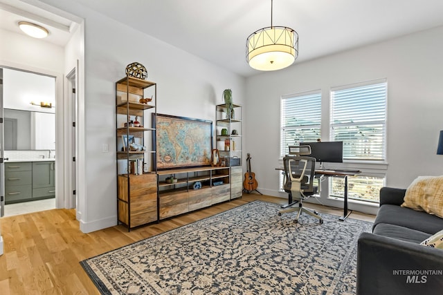 home office with light wood-style flooring and baseboards