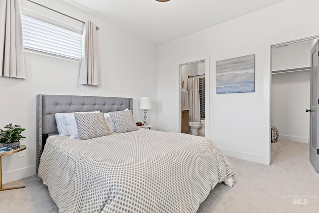 bedroom with a closet, light carpet, a spacious closet, and baseboards