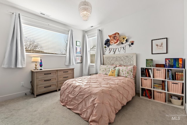 carpeted bedroom featuring baseboards, visible vents, and a notable chandelier