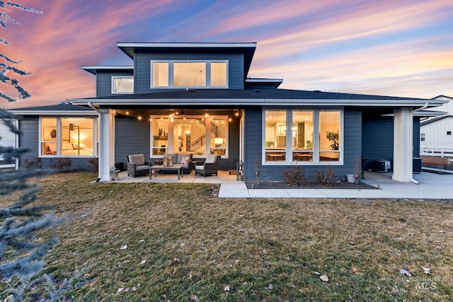 back of property at dusk featuring an outdoor hangout area, a patio, and a yard