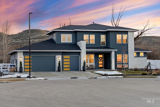 view of front of property featuring concrete driveway, an attached garage, fence, a mountain view, and a garage