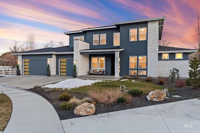 view of front facade featuring concrete driveway, stone siding, an attached garage, a porch, and stucco siding