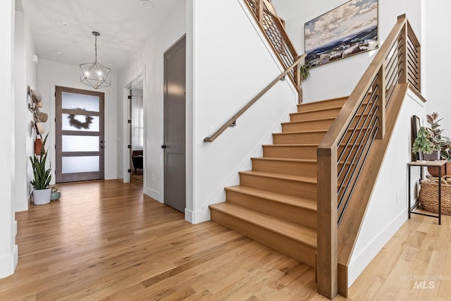 entryway featuring light wood-style floors, baseboards, stairway, and an inviting chandelier