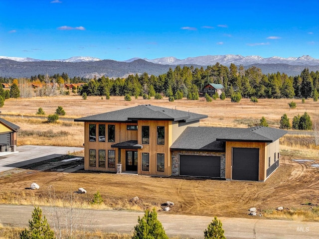 prairie-style house with a mountain view, a rural view, and a garage