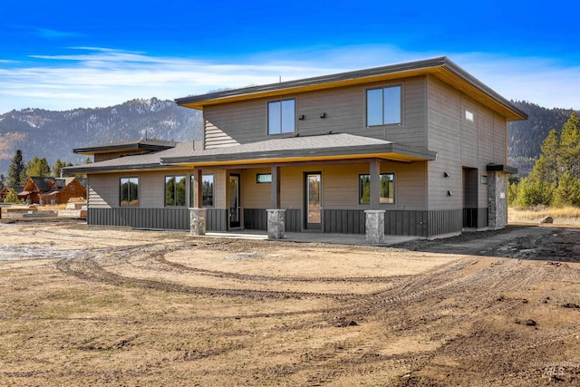 rear view of property featuring a mountain view and covered porch