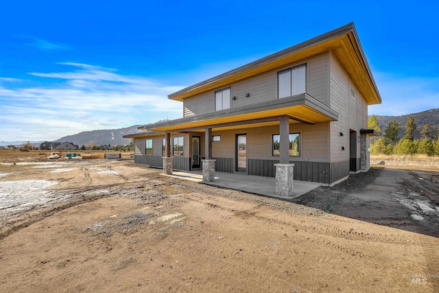 back of property with a mountain view and a porch