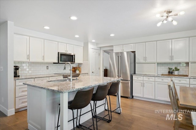5322 N Papago Pl, Boise, ID 83713 - kitchen with appliances with stainless steel finishes, backsplash, wood finished floors, white cabinets, and recessed lighting