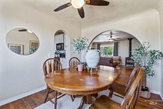 2524 Succor Creek Rd, Homedale, ID 83628 - dining space featuring a wood stove, ceiling fan, baseboards, wood finished floors, and arched walkways