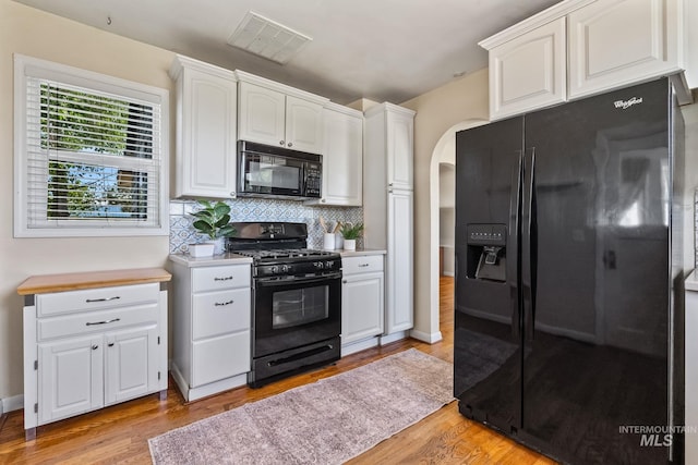 2524 Succor Creek Rd, Homedale, ID 83628 - kitchen featuring black appliances, light wood-style flooring, white cabinetry, arched walkways, and light countertops